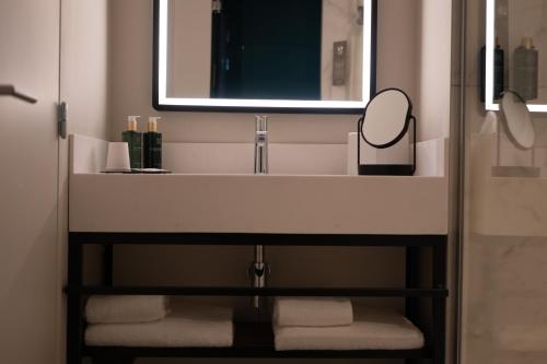 a bathroom with a sink with a mirror and towels at Hotel & Spa Oceania Lille Les Augustins in Lille