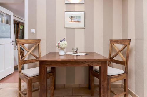 a wooden table with two chairs and a vase of flowers at WURZENBERG Hotel Lodges Südsteiermark in Gamlitz