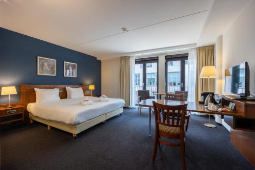 a hotel room with a bed and a desk and a television at Amrâth Grand Hotel Frans Hals in Haarlem