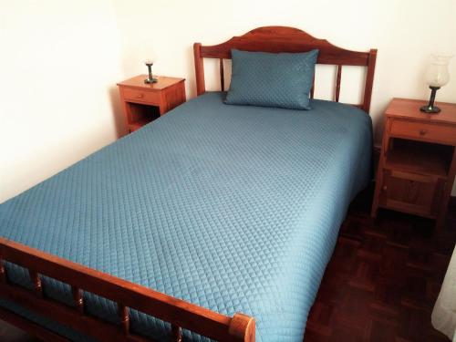 a bedroom with a bed with a blue bedspread and two tables at House Andrade in Praia do Norte