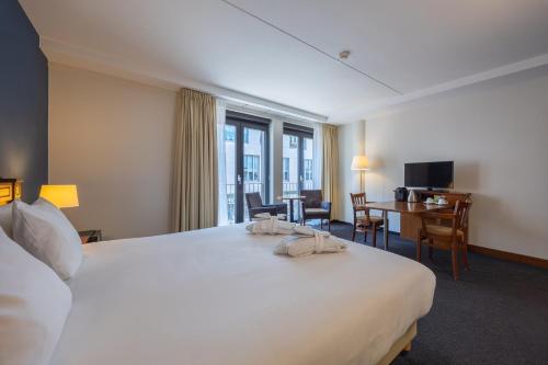 a hotel room with a large white bed and a desk at Amrâth Grand Hotel Frans Hals in Haarlem