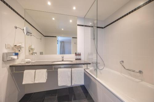 a bathroom with a tub and a sink and a shower at Amrâth Grand Hotel Frans Hals in Haarlem
