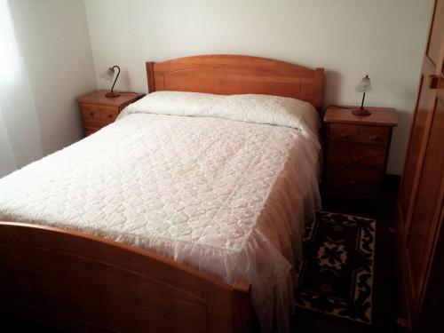 a bed in a bedroom with two night stands and two tables at House Andrade in Praia do Norte