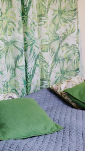 a green pillow on a bed with a wall at Hostelli Marja in Mikkeli