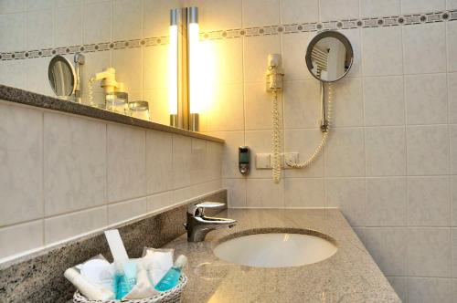 a bathroom with a sink with a mirror and a hair dryer at Hotel Essener Hof; Sure Hotel Collection by Best Western in Essen