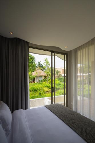 a bedroom with a bed and a large window at Mahutsachan Khlong Thom in Krabi town