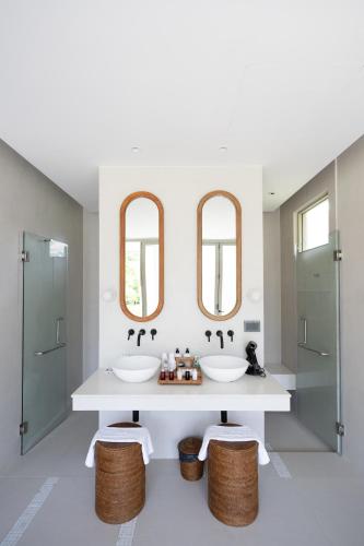 a bathroom with two sinks and two mirrors at Mahutsachan Khlong Thom in Krabi town