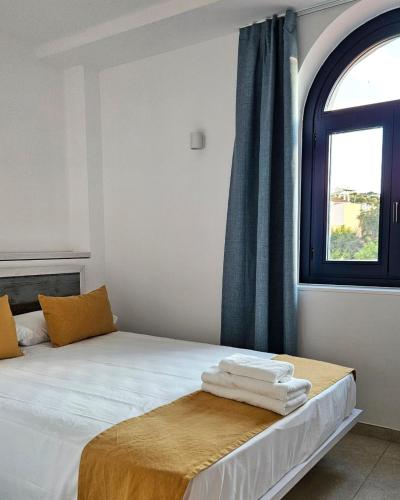 a bedroom with a bed with a window and towels at Hotel Boutique Es Blau in Cadaqués