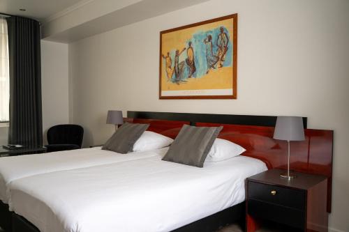 a bedroom with two white beds and a painting on the wall at Hampshire Hotel – Voncken Valkenburg in Valkenburg