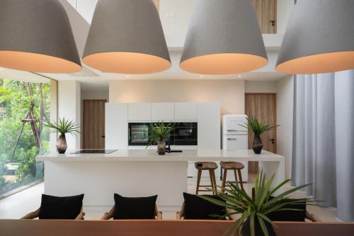 a kitchen with a counter and some chairs and lights at Mahutsachan Khlong Thom in Krabi town