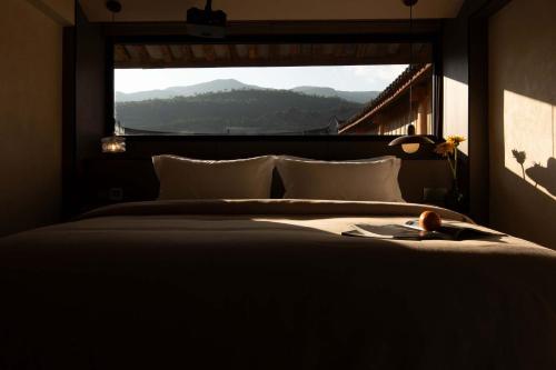 a bedroom with a large bed with a large window at Shuxia · Summer Lijiang Baisha Snow Mountain Scenic Hotel in Baisha