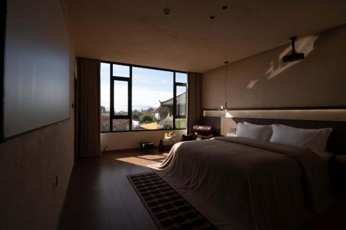 a bedroom with a large bed and a large window at Shuxia · Summer Lijiang Baisha Snow Mountain Scenic Hotel in Baisha