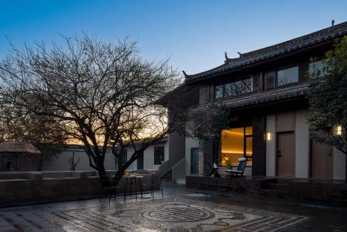 a house with a courtyard with a tree in front of it at Shuxia · Summer Lijiang Baisha Snow Mountain Scenic Hotel in Baisha