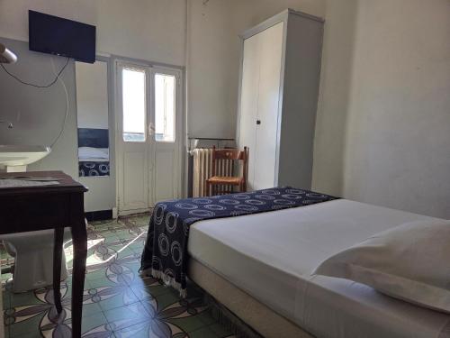 a bedroom with a bed and a desk and a window at Hotel Le Centre in Le Boulou