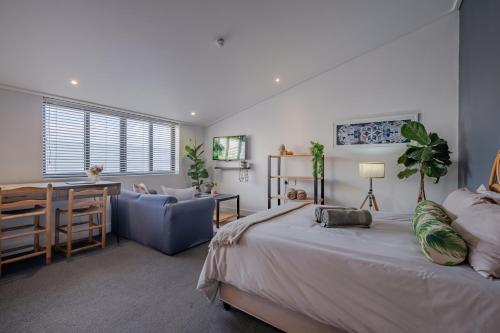 a bedroom with a bed and a desk and a chair at Hermanus Waterfront Boho Studio Apartment, Whale Coast Hideaway in Hermanus