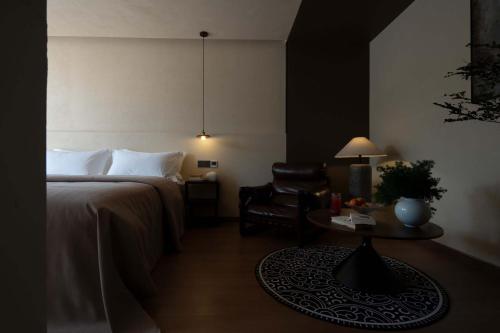 a bedroom with a bed and a chair and a table at Shuxia · Summer Lijiang Baisha Snow Mountain Scenic Hotel in Baisha