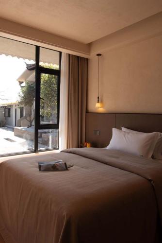 a bedroom with a large bed and a large window at Shuxia · Summer Lijiang Baisha Snow Mountain Scenic Hotel in Baisha