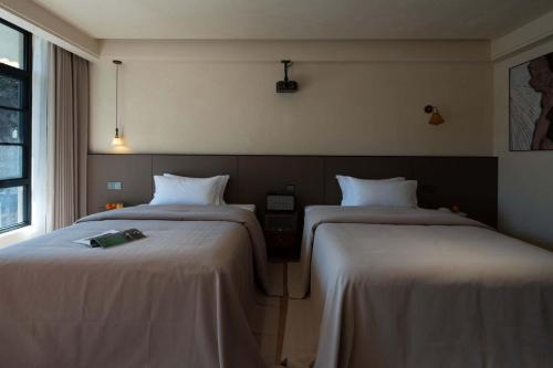 two beds sitting next to each other in a room at Shuxia · Summer Lijiang Baisha Snow Mountain Scenic Hotel in Baisha