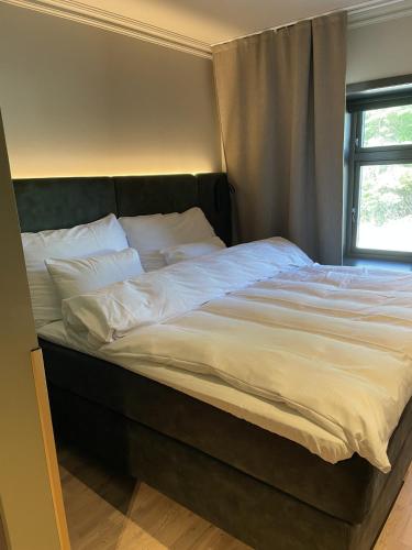 a large bed with white sheets and a window at Biologen Herdla in Askøy