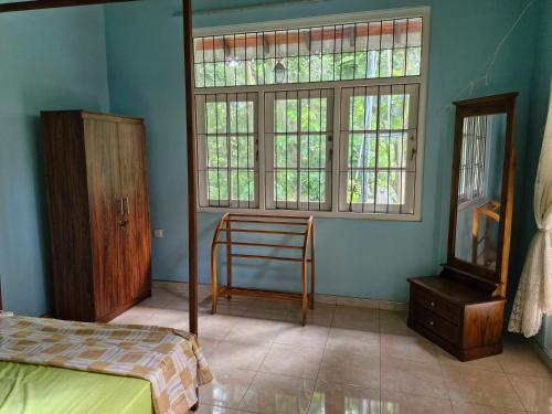 a bedroom with a bed and a window and a chair at Rose villa in Mahawewa