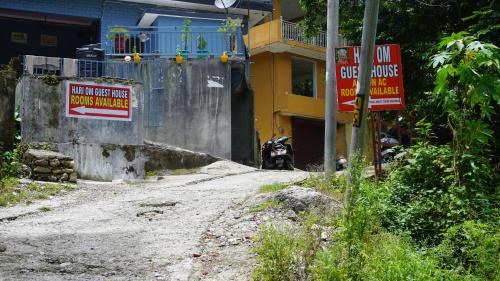 a dirt road with signs in front of a building at Hari Om Guest House in Narendranagar