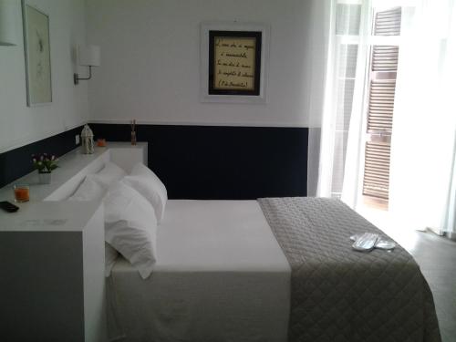 a bedroom with a white bed and a window at Novecento Dimore di Poesia in Trani