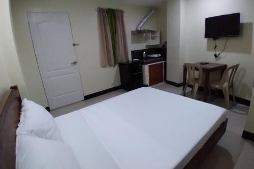 a bedroom with a large white bed and a desk at Chateau Cinco Near SM Lanang in Davao City
