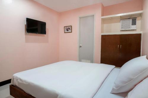 a bedroom with a white bed and a flat screen tv at Chateau Cinco Near SM Lanang in Davao City