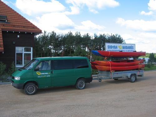 a green van parked next to a trailer with two canoes at Sodyba Pas Drambliuka in Svėdasai