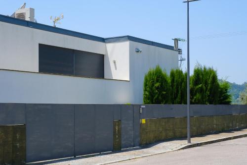 a white building with a black fence next to a street at Casa Horizontes de Arouca in Arouca