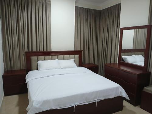 a bedroom with a large bed and a mirror at زهرة الوادي 1 للشقق المفروشة in Salalah