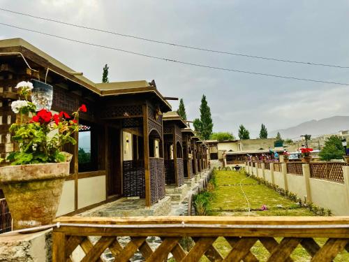a fence in front of a building with red flowers at Zimsa Resort Skardu in Skardu