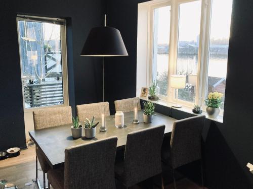 a dining room with a table and chairs and windows at Bolig i sjøkanten in Arendal