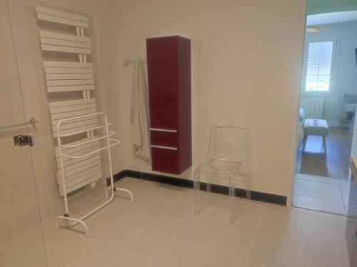 a room with a chair and a red cabinet at Le jardin d'Annie in Jaucourt