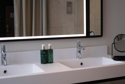 a bathroom with two sinks and a large mirror at Hotel & Spa Oceania Lille Les Augustins in Lille