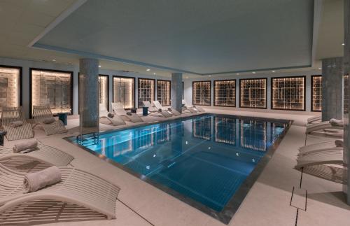 a large swimming pool with white lounge chairs at Hotel & Spa Oceania Lille Les Augustins in Lille