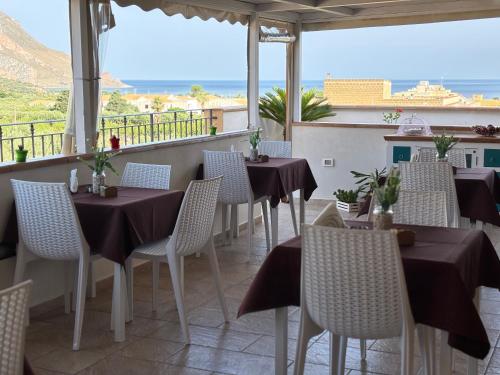 Um restaurante com mesas e cadeiras e vista para o oceano. em Triskell Camere & Relax em Castelluzzo