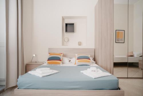 a bedroom with a bed with blue sheets and colorful pillows at Central Station by CasaNapoletana in Naples
