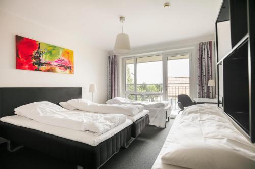 a room with three beds and a window at Fjelsted Skov Hotel & Konference in Ejby