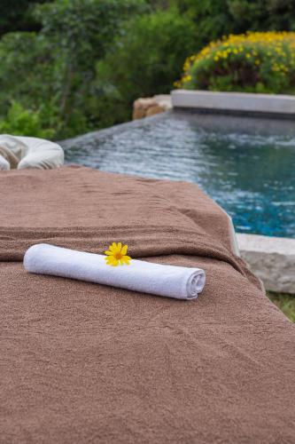 a white towel with a flower on it next to a pool at Domaine de la Cascade Parfumée in Grasse