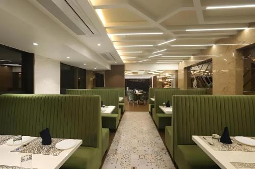 a dining room with green chairs and tables at Hotel Auris & Banquets, Mumbai International Airport in Mumbai