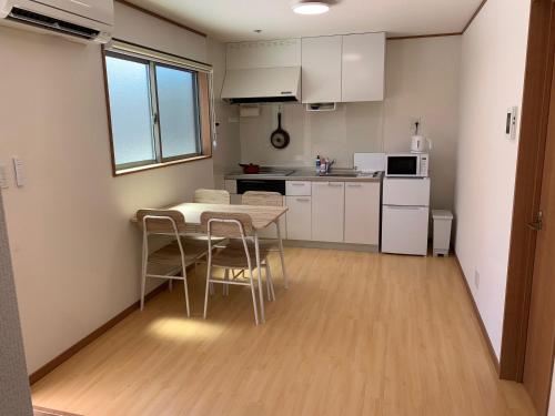 a kitchen with a table and chairs in a room at Guesthouse IKETA in Niijimamura