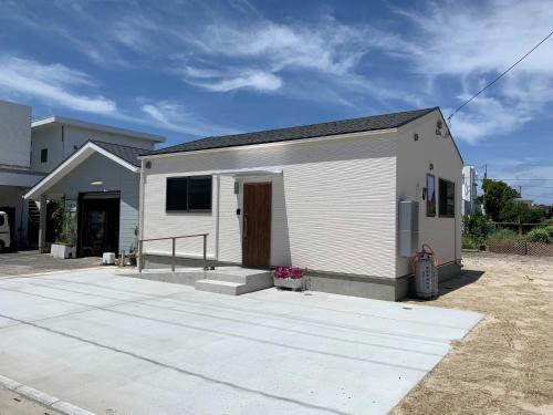 a small white house with a garage at Guesthouse IKETA in Niijimamura
