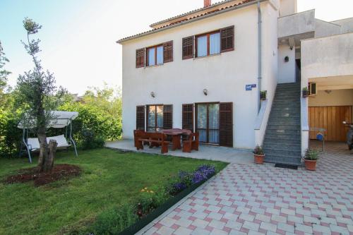 a house with a patio and a yard at Apartments Milovan in Fažana