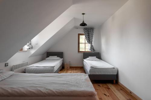 a attic room with three beds and a window at Osada Dębno 