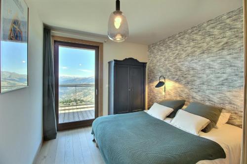 ein Schlafzimmer mit einem großen Bett und einem großen Fenster in der Unterkunft ARC 1600, LE RIDGE, Appartement 08 personnes Vue Montagne - ski aux pieds - Sauna, Hammam, Piscine in Arc 1600