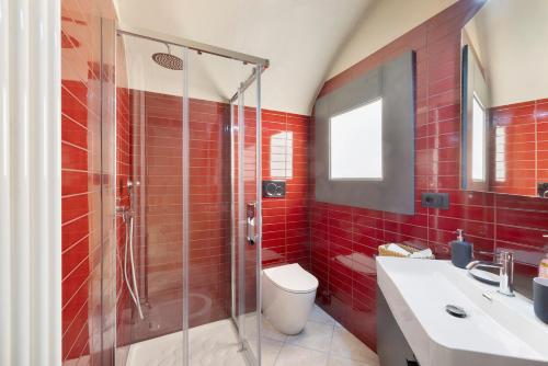 a red tiled bathroom with a toilet and a shower at Il Cappellaio Matto in Alessandria
