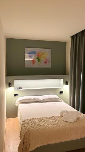 a bedroom with a white bed with a green wall at Hotel Milazzo Smart in Milazzo