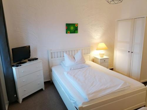 a bedroom with a white bed and a television at Pension Sonnenhof in Braunlage