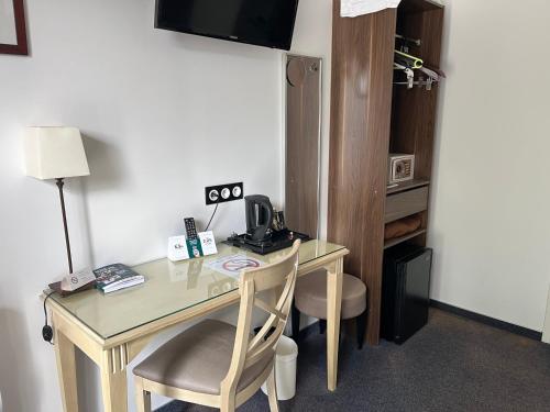 a desk with a chair and a table with a telephone at Logis Hotel-Restaurant "Auberge Le Petit pont" in Tennie